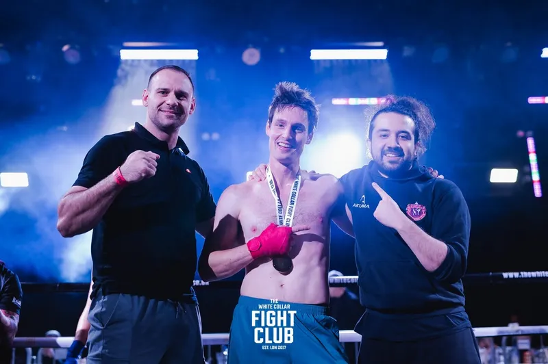 One of Alex's athletes wearing his medal after a bout, between Alex (right) and Alex's own coach (left).